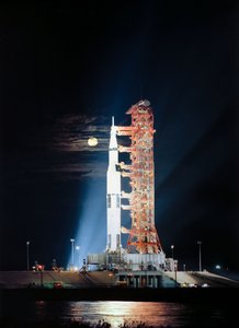 サーチライトに照らされた夜のフロリダ州ケネディ宇宙センターの発射場39のAパッドで、打ち上げ前の準備中のアポロ17号（宇宙船114号/月着陸船12号/土星512号）を撮影。 作： Unbekannt