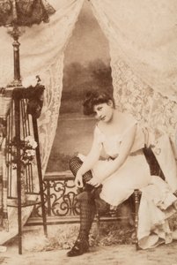 靴紐を締めながら座る、親しげな服装の若い女性の肖像。 作： Unknown photographer