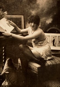 テーブルに座って本を読む、親しげな服装の若い女性の肖像。 作： Unknown photographer