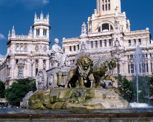 1782年にヴェントゥーラ・ロドリゲス（1717-1785）によって建設された、2頭のライオンに引かれた荷車に乗った女神サイベレの噴水（後ろ）、マドリッドのシベレス広場にある通信宮の風景（写真 作： Ventura Rodríguez