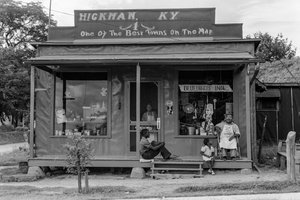 アフリカ系アメリカ人の男女が、小さな雑貨店のポーチでくつろいでいる。