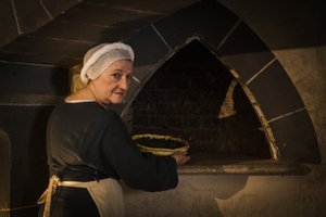 歴史の再現。お城のキッチンのオーブンにケーキを入れるメイドさん
