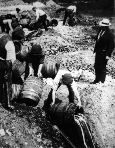 アメリカの禁酒法時代（1920〜33年）にビール樽の破壊を監督する米国連邦捜査官（モノクロ写真）。 作： American Photographer