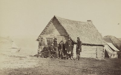兵士のグループと1人のアフリカ系アメリカ人である2人の若い男性は、1861年から65年の丸太小屋の外に立っています。 作： American Photographer