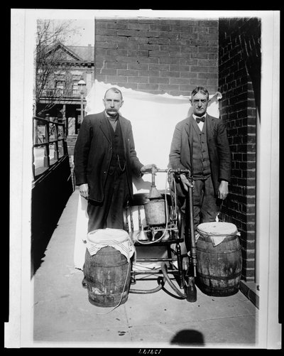 ウイスキーの蒸留器を持ってポーズをとる2人の男性 作： American Photographer