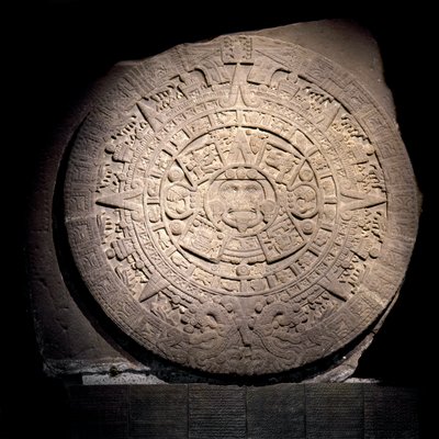 先コロンブス文明：アステカの暦（太陽の石）：アステカの暦と宇宙観を表す直径3mの石の円盤で、中央の金色の部分は太陽トナティウの神格を表している、テノチティトラン（メキシコシティ）から来ている、国立人類学博物館 作： Aztec Aztec