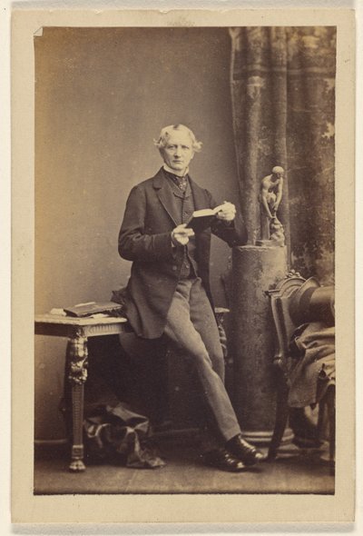 [テーブルの上に座り、開いた本を持っている正体不明の男] 作： Camille Silvy