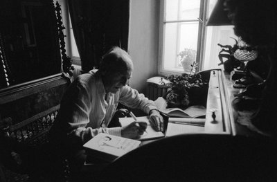 プラハのフラドチャニにある家の机に座っているイリ・ムチャ 作： Czech Photographer