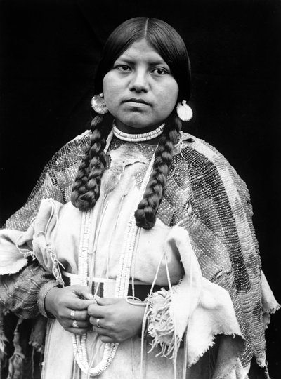 Mulher Cayuse, retrato de meio corpo, em pé, de frente, tranças, brincos de disco de conchas, gargantilha de contas e contas de conchas no pescoço, vestido de camurça frisado com cinto de contas c. 1910, foto Edward S. Curtis 作： Edward Sheriff Curtis