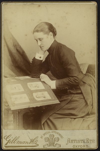 写真アルバムを見ながら座っている女性の姿 作： English Photographer