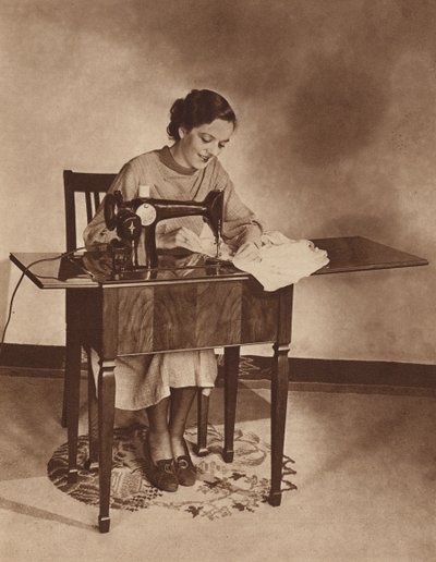 ミシンで仕事をする主婦、1930年代半ば（モノクロ写真） 作： English Photographer