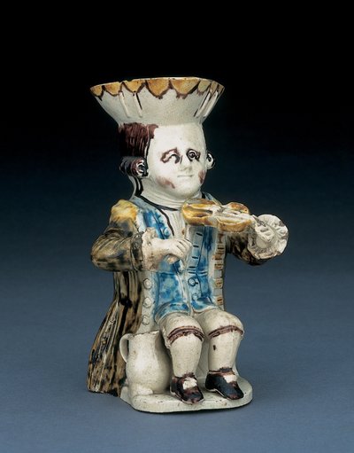 フィドラーのトービージャグ、茶色と黄色のスカラップで縁取られた帽子、茶色の髪を切り込み、白いロゼットで列に並べ、洗った茶色のフロックコート、c.1770 作： English School