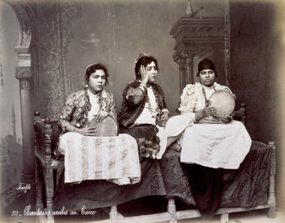長いネックレスを持つ民族衣装の3人の若いアラブ歌手の肖像画。彼らは座っているスタジオでポーズをとっています。 2人はタンバリンを持っています 作： Félix Bonfils