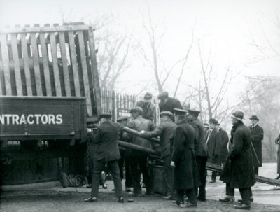 1924年にロンドン動物園で飼育員がサイからトラックから荷降ろしされると、見物人の群衆が待機します。 作： Frederick William Bond