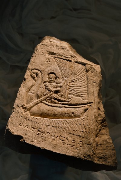 舟に横たわる少年を描いた石灰岩の葬祭用ステラ、ローマ時代、2002年（写真）。 作： Kenneth Garrett