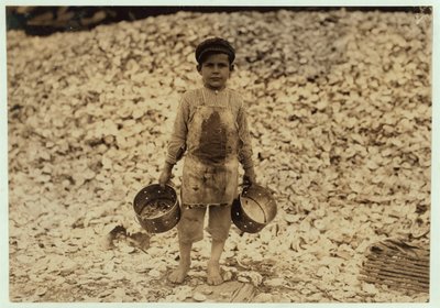 1911年、ミシシッピ州ビロクシにあるダンバー、ロペス、デュケイトカンパニーで2年目を過ごした、カキの殻の山の前で働く5歳の移民エビピッカーマヌエル 作： Lewis Wickes Hine