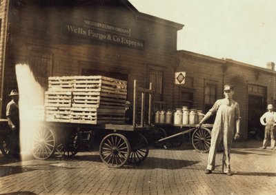 1916年、ミズーリ州スプリングフィールドにあるクレートとミルク缶を備えたウェルズファーゴウントコエクスプレスデポの前に立つ男性 作： Lewis Wickes Hine