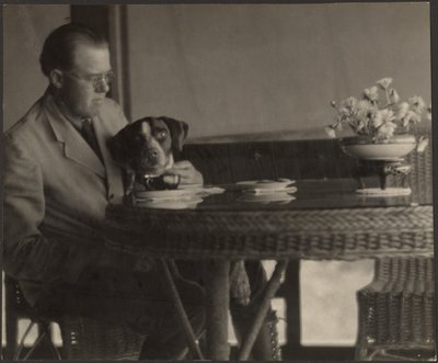 [テーブルに座る男と犬] 作： Louis Fleckenstein