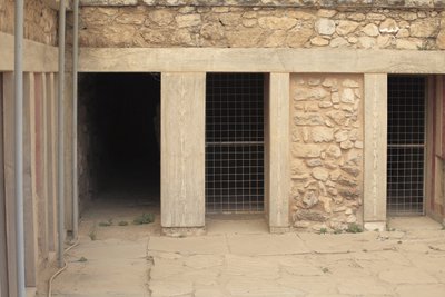 ミノア人の考古学的遺跡クノッソス。三つ子の祠」の隣にある西翼。床に沈んだ2つの大きな長方形の貯蔵庫がある部屋。粘土製の壷や貴重な品々が収められており、その中には有名な「蛇」の像もあった。 作： Minoan