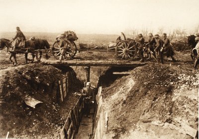 敵の塹壕の上を横切る野砲。敵の陣地を克服するために、砲車にはファシネの束が固定されている（モノクロ写真）。 作： Photographer German
