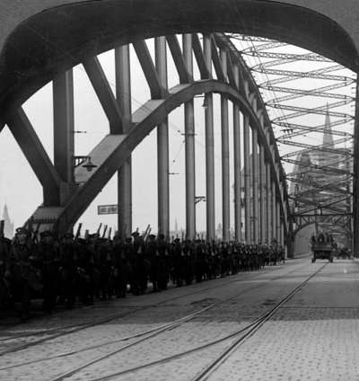 1918〜1926年、ドイツのケルンのライン川に架かる橋を渡るイギリス軍。 作： Realistic Travels Publishers