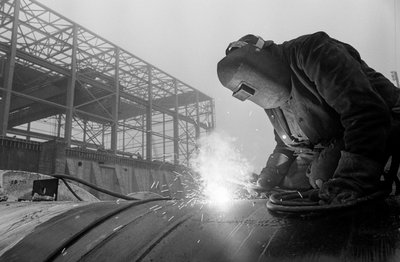ハンフォアの建設現場で、アセチレン・トーチを使って工業用パイプを溶接する溶接工。 作： Ted Spiegel