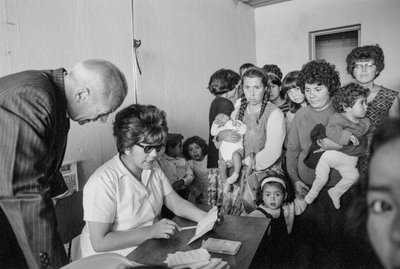 サンティアゴの診療所を訪れた子供と赤ん坊を連れた若い母親たち。 作： Ted Spiegel