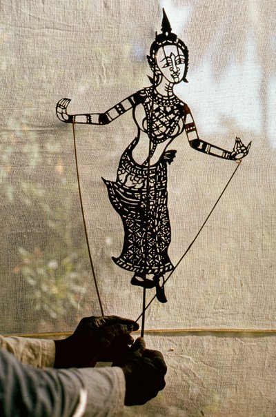 影絵芝居のためにスクリムに向かって紙芝居の影絵を操る人形遣い。C... 作： Thomas J. Abercrombie