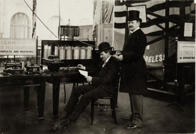 1904年の万国博覧会の電気部門で無線電話のメッセージを送るLee DeForest氏（着席）。 作： Unbekannt