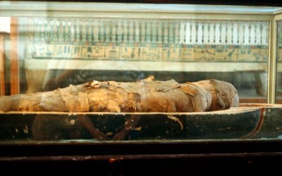 包帯で包まれ、古代エジプト人の棺のふもとに横たわっているミイラ 作： Unbekannt