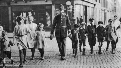1926-1927年、ロンドンのイーストエンドにある道を渡る児童を助ける警官 作： Unbekannt