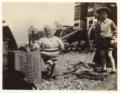 水浴マシンのそばにいる2人の子供, 1895年頃, 海岸で水浴マシンの集団の中に立っている2人の子供のスナップショット写真 作： Unbekannt