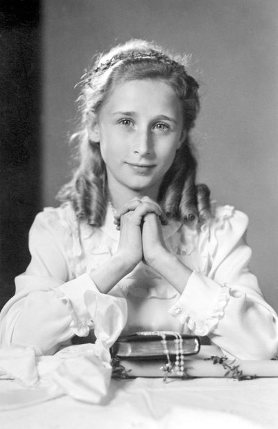 両手を合わせて祈りの姿勢をとるクリスチャンの少女と聖書、ロザリオ、ろうそく（聖体拝領の写真）。1932年頃の写真 作： Unbekannt