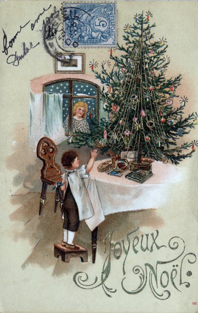 クリスマス・グリーティングカード：テーブルの上に置かれたクリスマスツリーの前でポーズをとる子供と、窓から見える天使 - 1905年のポストカード 作： Unbekannt