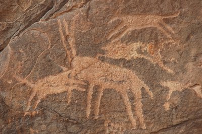 ロックアート、先史時代。エジプト、ウワイナット山地の犬の群れに襲われたカモシカの彫刻（紀元前8000年から3000年の時代写真 作： Unbekannt