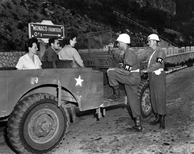 第二次世界大戦(1939-1945) - World War II (WWII or WW2):モナコフレンチリビエラ付近 1945年6月30日。米国リビエラ保養地（USRRA）のゲストである休暇中の2人のワックが、モネの端に駐留する2人の米軍憲兵と話し合う 作： Unbekannt