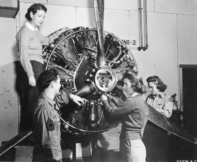 ロックボーンAABで行われたB-17パイロットトレーニングに参加し、B-17フライングフォートレスのエンジンの動力源を学ぶスズメバチたち。 クルーチーフが見守る中、プロペラのメカニズムに取り組む（左から右）。パトリシア・バウザー、アン・ウォルドナー、フランシス・グリーン 作： Benjamin Baud