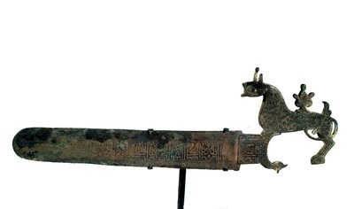 ブロンズ製のノコギリで、刃には文字が刻まれています。動物の形をしたハンドル 作： Unknown artist