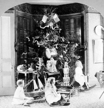 クリスマスの朝、プレゼントに囲まれてツリーの足元に集まる子どもたち。 作： Unknown photographer