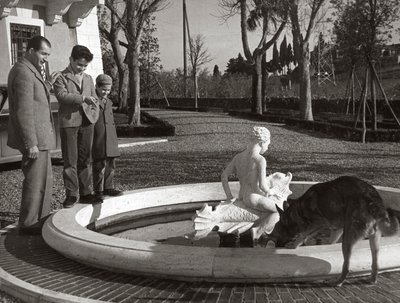 噴水の近くで2人の子供と犬を連れたジーノ・バルタリ 作： Unknown photographer
