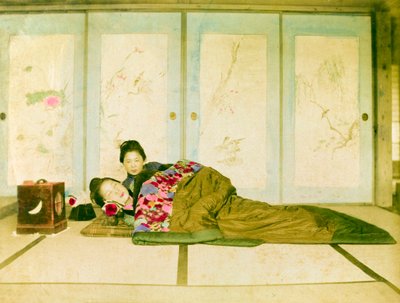 布団の上でリクライニング。床に敷かれた伝統的な布団の上でリクライニングする2人の日本人女性。日本、1910年頃。日本、東アジア、アジア。©Cultural Heritage Images/UIG/Leemage 作： Unknown photographer