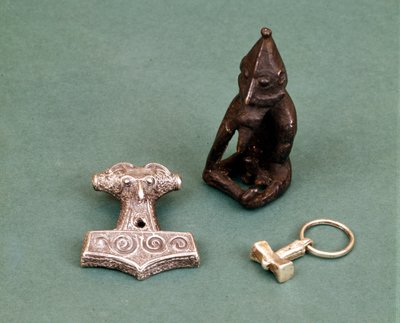 ヴァイキングの神々のお守り：手前にはトール神を象徴する2つの小さな銀のハンマーがある。像は豊穣の神フレイアを表している。スウェーデン、ストックホルム歴史博物館 作： Viking Viking