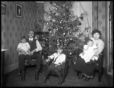 1915〜16年頃、ニューヨーク市のクリスマスツリーの前に座っているアパートでの正体不明の家族の非公式のグループポートレート 作： William Davis Hassler