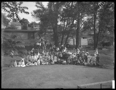 正体不明の遊び場で集団の肖像画のために集まった子供たちの大規模なグループ、1910年頃 作： William Davis Hassler