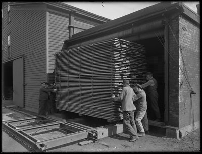 1916年4月3日、ニューヨーク州オナイダのドライキルンから棺の製造に使用することを意図した木材を取り除く 作： William Davis Hassler