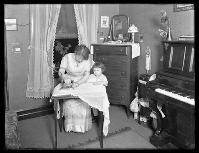 少女が見守っていた、電気アイロンの使用を示す身元不明の女性、c.1913-14 作： William Davis Hassler