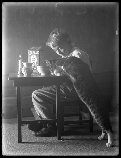 ウィリアム・グレイ・ハスラーと猫のレディ、クエーカー教徒のパフライスシリアルを食べる、1912年頃 作： William Davis Hassler