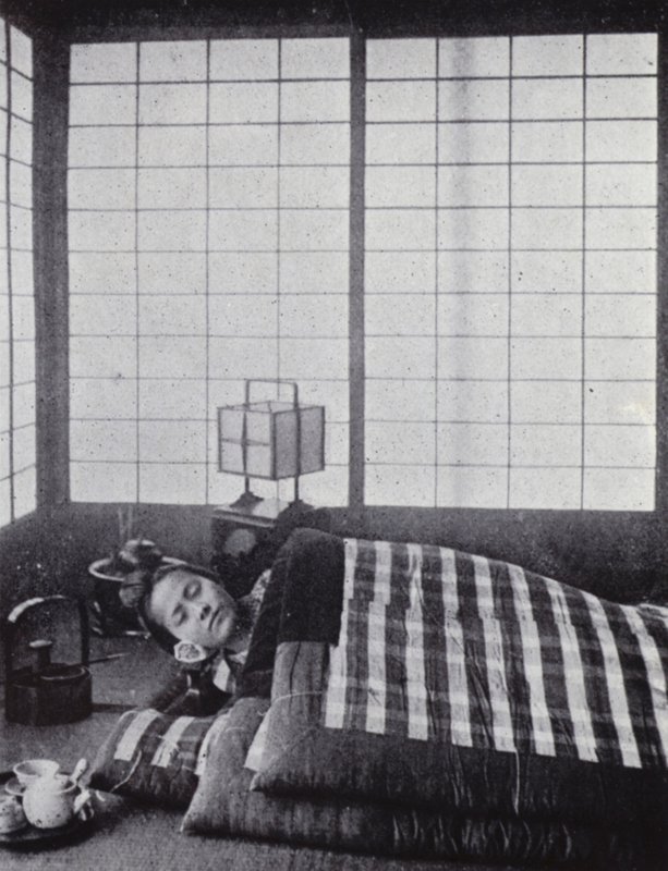 木製の枕を持って、わたがしのような布団の間で眠る少女（モノクロ写真 作： アメリカの写真家（後）