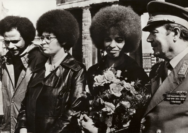 1972年9月11日、アメリカの共産主義者で公民権運動家のアンジェラ・デイヴィスは、ドイツ民主共和国の国家人民軍の兵士たちからブランデンブルク門で心のこもった歓迎を受けた（モノクロ写真）。 作： 写真家ドイツ語