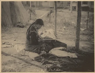 [ビーズ細工に取り組むメスクワキ民族の女性]。
